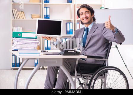 Young handsome employee in wheelchair at the office Stock Photo