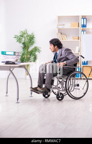Young handsome employee in wheelchair at the office Stock Photo