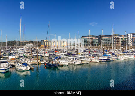 Castle Quay in Saint Helier on the Jersey on the Channel Islands. Shows many luxury boats moored up under a blue summer sky.