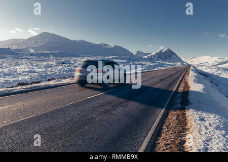 Car driving on open road winter snow mountain landscape in Glencoe Scotland Stock Photo