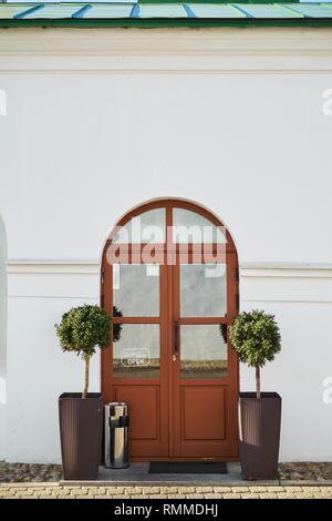 Two small decorative trees either side of a front door entrance to European cafe Stock Photo