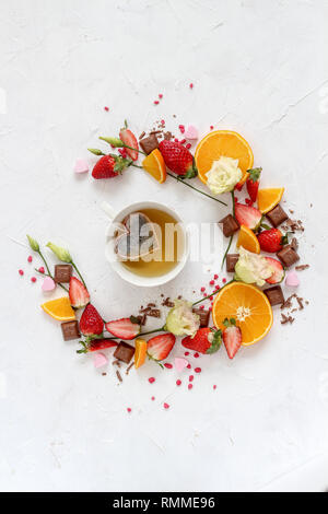 Circle composition of mixed fruits and a cup of tea with heart shape tea bag in the middle on a bright background Stock Photo
