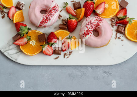 A mixed fruit platter with doughnuts on a dark background Stock Photo