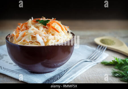 In a ceramic Cup on an old wooden table sauerkraut with carrots. Stock Photo