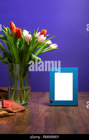 Fresh tulip flowers bouquet in flower vase and photo frame. Fresh tulip flowers bouquet with mockup photo rame on wood table Stock Photo
