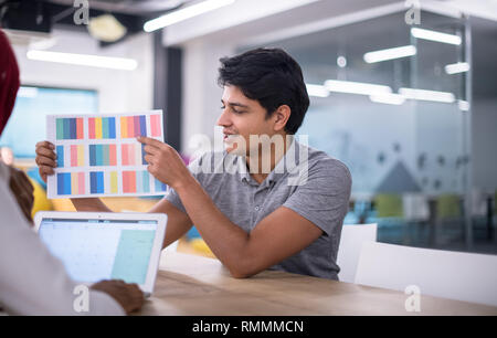 successful black muslim business woman having a meeting with her indian male colleague working on the laptop at modern startup office Stock Photo
