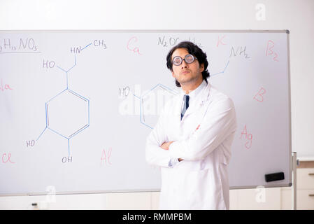 Young funny chemist in front of white board Stock Photo