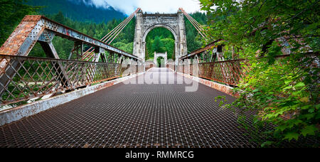 Lillooet, B.C., Canada - June 30, 2012: Low angle view of a rusty metal suspension bridge over the Fraser river Stock Photo