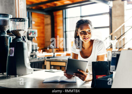 Cafe owner using digital tablet at counter Stock Photo