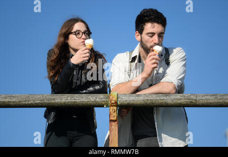 A couple eat ice-creams on Brighton seafront. Forecasters have predicted another day of warm weather on Friday after the unseasonably mild weather saw the warmest Valentine's Day in more than 20 years on Thursday with a maximum of 16.1C (61F) recorded in the Welsh town of Bala, Gwynedd. Stock Photo