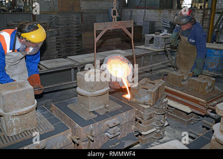 GREYMOUTH, NEW ZEALAND, MAY 17, 2016: Foundrymen pour molten iron into moulds for making fire grates Stock Photo