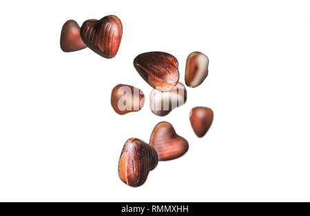 Chocolate hearts floating on isolated white background. Valentines romantic theme with white and brown candy hearts, background removed. Stock Photo
