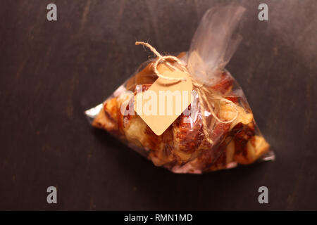 Fresh homemade French croissants with filling in a transparent cellophane bag with a tag on a black table Stock Photo