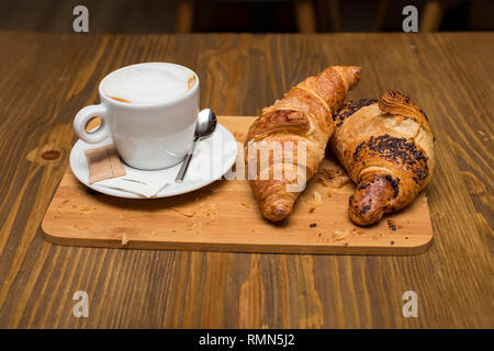 View at traditional french breakfast with cups of hot coffee and fresh tasty croissants placed on vintage table Stock Photo
