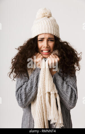 Upset young woman wearing winter scarf standing isolated over white background, shivering Stock Photo