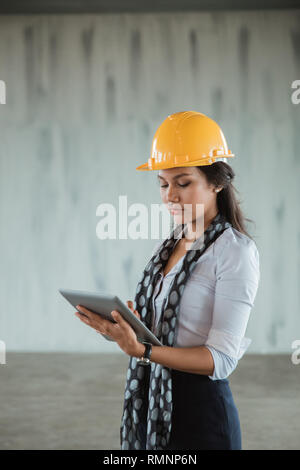 attractive businesswoman with hardhat using tablet pc in the project site Stock Photo