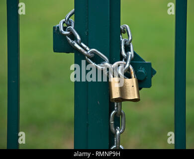 Padlock with chain locking gate on a field Stock Photo