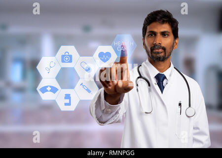 Male indian physician touching health care text button on futuristic screen with symbols as medical technology concept Stock Photo