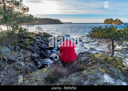 man in red jacket overlooking lake Vattern in Motala Sweden Stock Photo