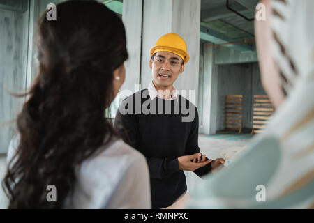 Businessman with protective hardhats working together and discussing details of design project on site Stock Photo
