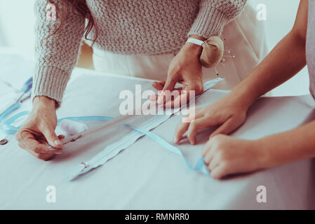 Best choice. Close up of hardworking family choosing a zipper for new dress while standing at the table Stock Photo