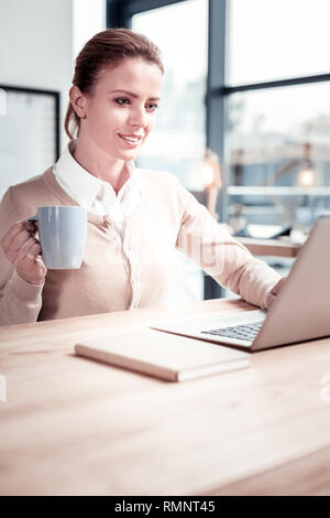 Freelance translator. Charming beginner freelance translator feeling impressed while translating new fantasy book on laptop Stock Photo