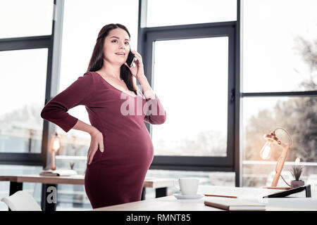 Calling taxi. Industrious skillful journalist feeling relieved while calling taxi from office heading home Stock Photo