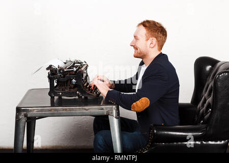 Young man in a suit typing on a typewriter Stock Photo