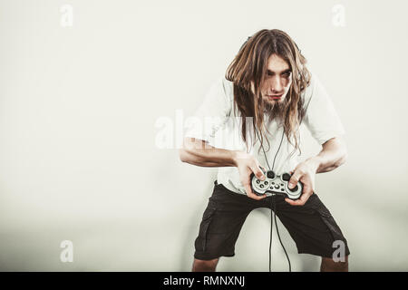 Lifestyle of young people. Student man spending time on playing games videogames console playstation. Long haired guy focus on gaming. Stock Photo