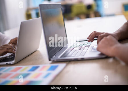 Young modern black muslim business woman wearing a red hijab,working on laptop computer in startup office. Diversity, multiracial concept Stock Photo