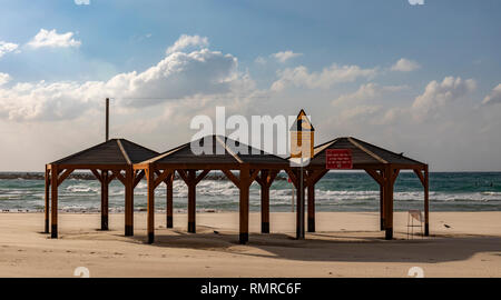 A deserted sandy beach in Tel Aviv, Israel, with a tsunami warning sign on one of its pavilions. Stock Photo
