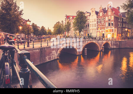 View of the City of Amsterdam with canal and bridge seen at sunset with vintage filter Stock Photo
