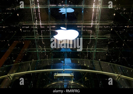 The lighted white logo of Apple at a flagship store in New York City's 5th Avenue at night. Stock Photo