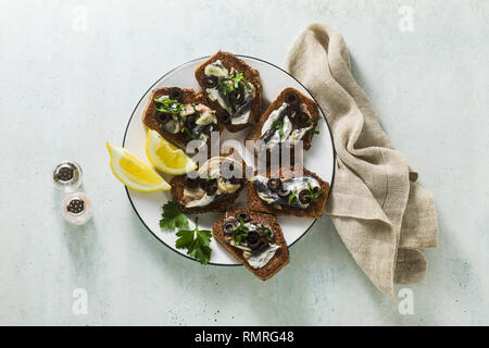 sandwiches with sardines marinated in olive oil with garlic and rye bread. summer light italian appetizer with lemon and parsley Stock Photo