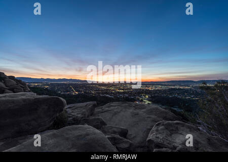 Rocky hilltop predawn view of San Fernando Valley neighborhoods and the San Gabriel Mountains in the city of Los Angeles, California. Stock Photo