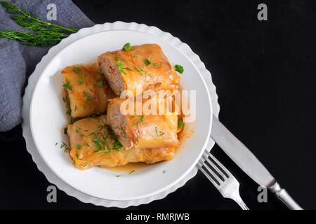 Stuffed with minced meat and rice, served on a plate . Presented close - up on a dark background. Stock Photo