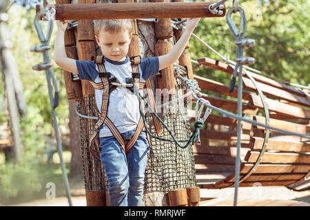 Little boy overcomes an obstacle in the cable park. Stock Photo