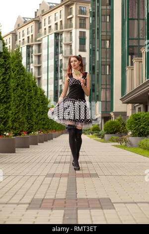attractive young woman with candy in black dress posing on street Stock Photo