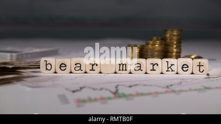 Words BEAR MARKET composed of wooden letter. Stacks of coins in the background. Closeup Stock Photo