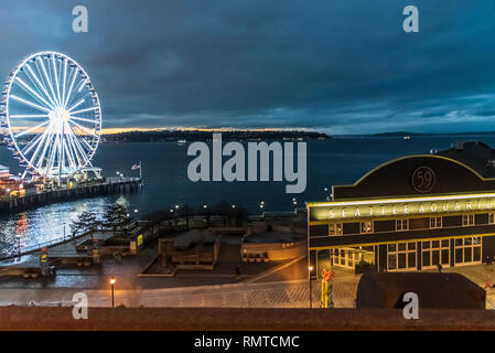 The Seattle downtown waterfront at dusk with the Ferris Wheel and tourist shops on piers. Stock Photo