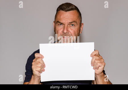 Mature man holding white sheet of paper with copy space Stock Photo