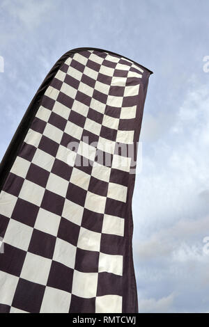 Tall checkered flag waving in the wind against the sky background