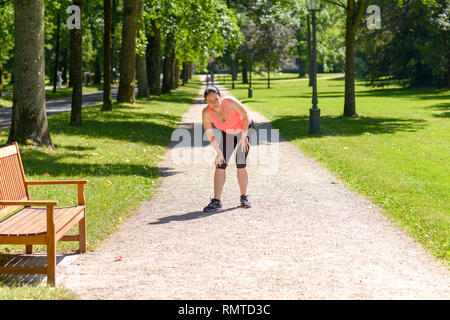 Woman holding her painful knee after exercising in park Stock Photo