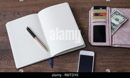 notebook with pen, wallet with money and discount cards, phone, on wooden background Stock Photo