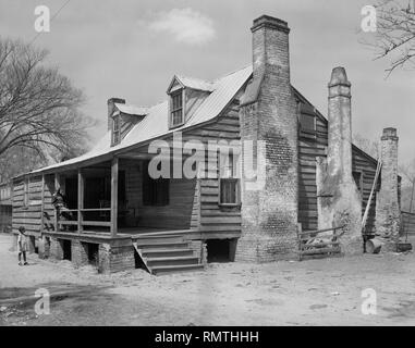 Man Sitting on Porch of Wood House while Young Girl Stands in Front Yard, Georgetown, South Carolina, USA, Frances Benjamin Johnston, 1937 Stock Photo