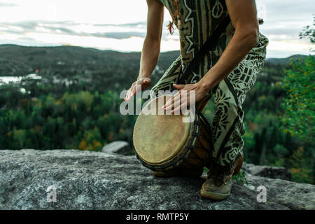 Man dressed with traditionnal clothes playing djembe on the top of a mountain Stock Photo