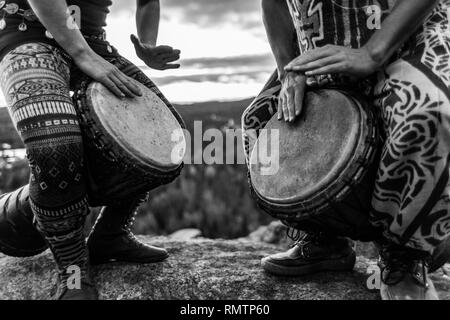 Man and woman playing djembe on the top of a mountain, black and white Stock Photo