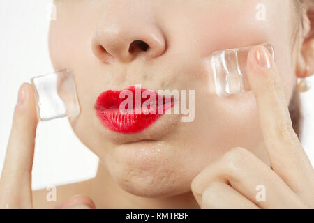 serious young woman applying ice cubes on her face skin, isolated on white background Stock Photo