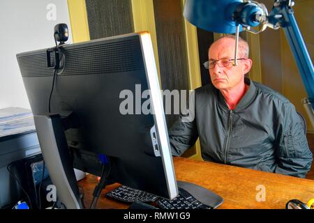 Middle aged man with glasses sitting at desk. Mature man using personal computer. Senior concept. Man working at office Stock Photo