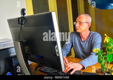 Businessman sitting in an office at the . Middle aged man with glasses sitting at desk. Mature man using mobile phone. Senior concept Stock Photo